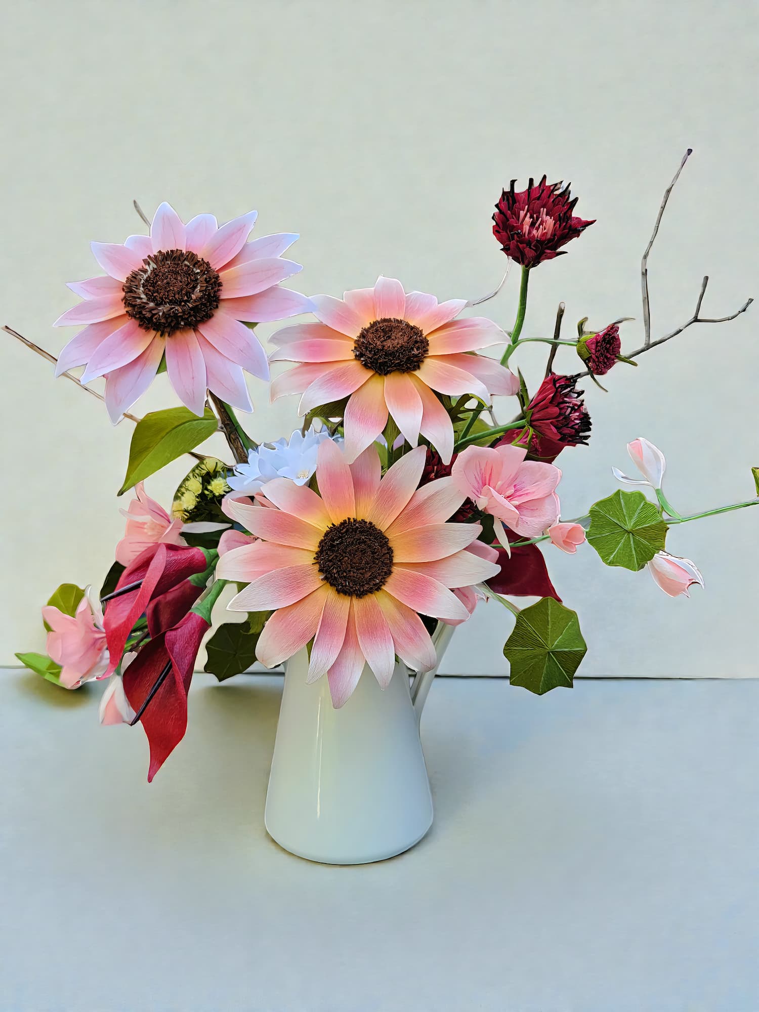 Bouquet of pink paper daisies in a white pitcher