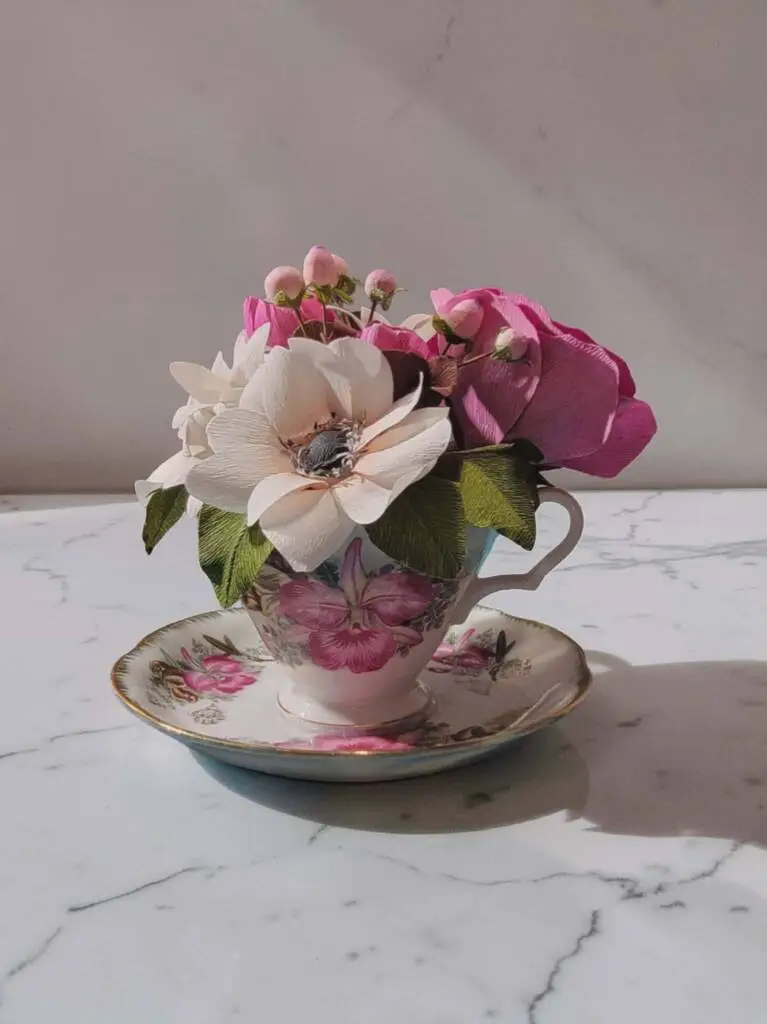 A small teacup with anemone, berries, and leaves