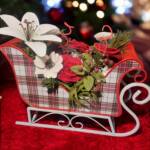 A small Christmas sleigh with lilies, roses, anemone, and berries.
