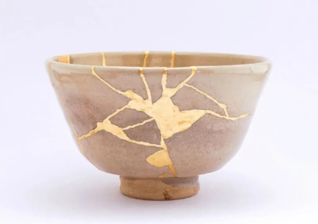 A small beige clay bowl with Japanese kintsugi markings.