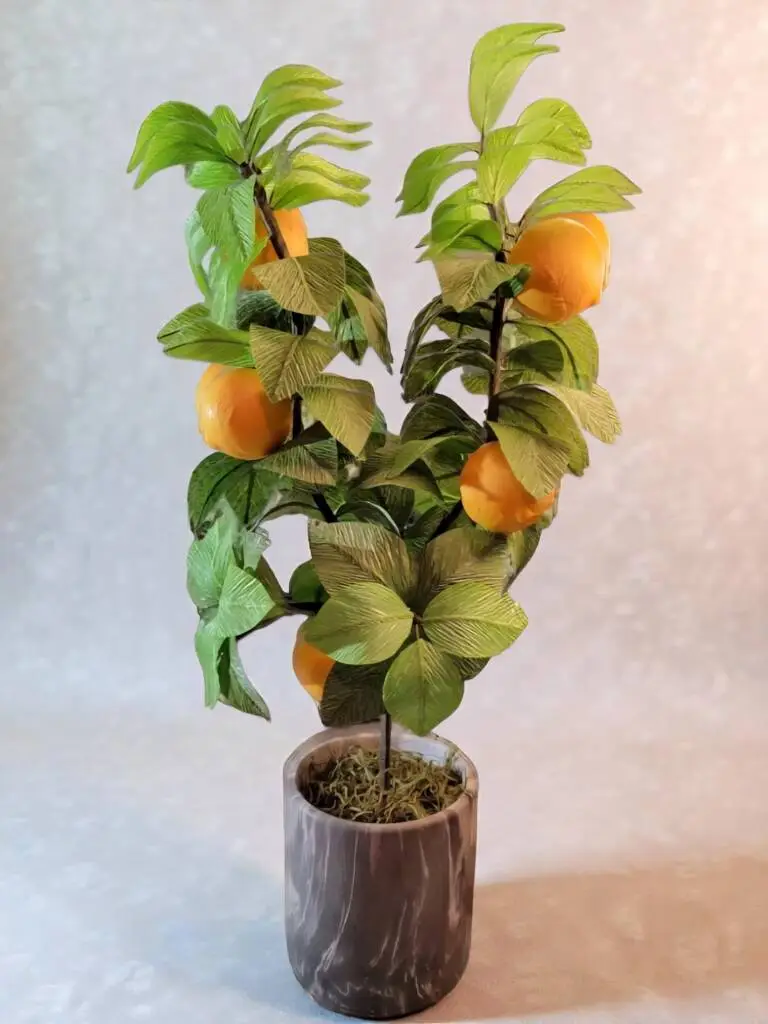 A small orange tree in a marble pot