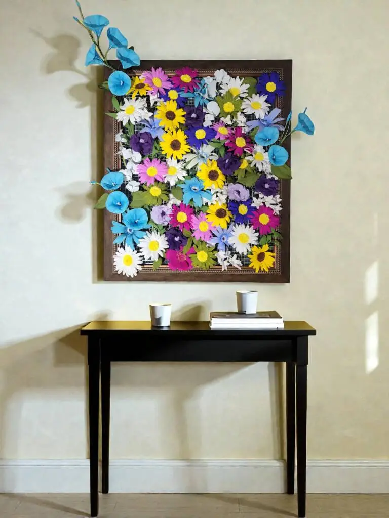 A photo frame filled with hand made flowers above a console table.