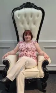 Photo of Miranda, founder of Momenti by Miranda, sitting in a black and white high back chair.